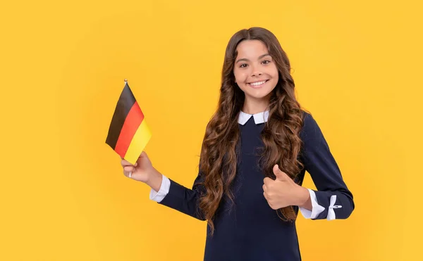 Feliz adolescente chica hold alemán bandera amarillo fondo mostrando pulgar hacia arriba, estudiar en el extranjero — Foto de Stock