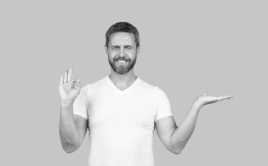 Mutlu adam elini açıp halka hareketi yapıyor. Gri arkaplan fotokopi alanı, ürün sunumu.