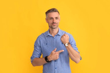 Olgun erkek işaret parmağı sarı arka planda saat, zaman