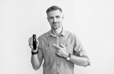 Sarı arka planda elektrik traşı gösteren, tıraş olan adam.