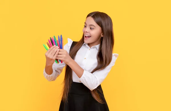 Menina feliz criança segurar feltro-dicas fundo amarelo, artigos de papelaria escola — Fotografia de Stock