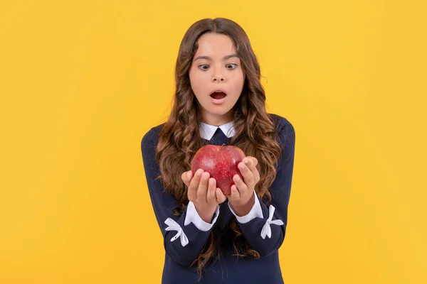 Geschokt kind kijken naar rode vitamine appel voor de lunch op gele achtergrond, detox — Stockfoto