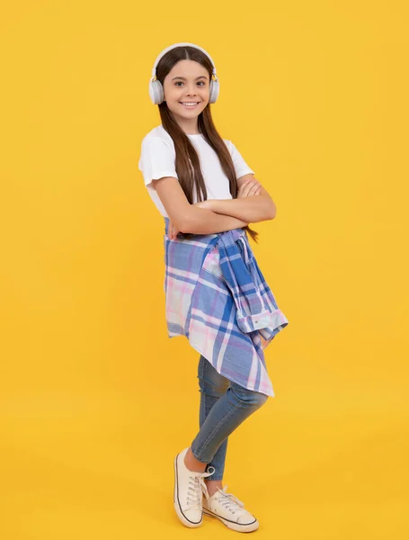 Criança feliz em casual ouvir música em fones de ouvido fundo amarelo, melomaníaco — Fotografia de Stock