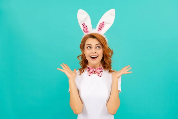 Счастливая изумленная пасхальная девушка в кроличьих ушах и галстуке-бабочке на голубом фоне — стоковое фото