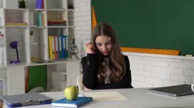 Düşünen genç kız sınıfta ödev okuyor. Bilgi günü.