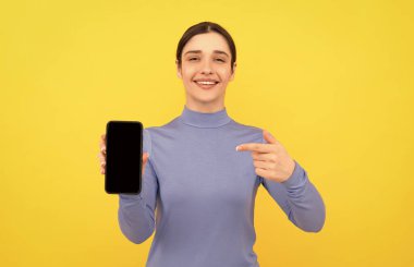 Akıllı telefonu işaret eden gülümseyen bayan, buraya bak.