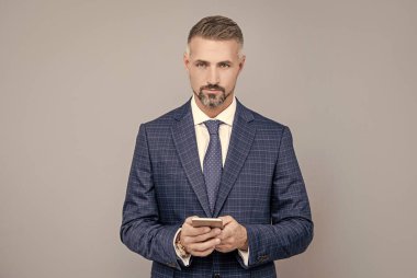 Takım elbiseli kendine güvenen işadamı telefonda mesaj yazıyor, blog yazıyor.