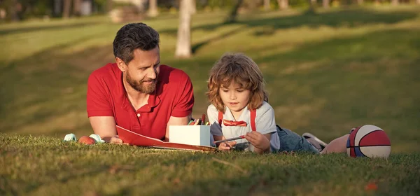 Padre e hijo relajarse en la hierba en el parque aprendiendo a dibujar, paternidad — Foto de Stock