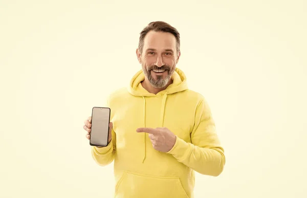 Счастливый человек представляет экран смартфона указывая пальцем на пространство для копирования, представляя продукт. — стоковое фото