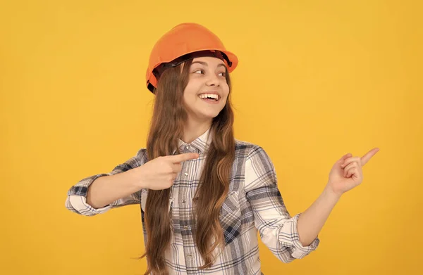 Menina adolescente feliz no capacete e camisa quadriculada apontando dedo no espaço cópia, anúncio — Fotografia de Stock