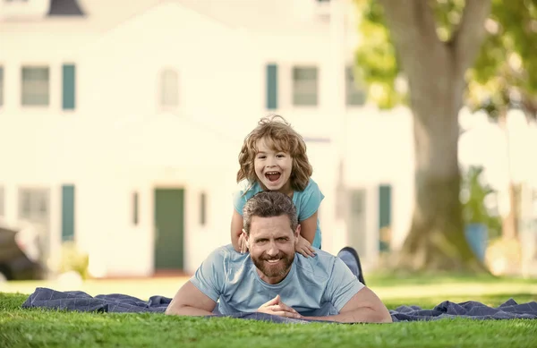 Feliz hijo niño paseo padres espalda relajarse en manta puesta en hierba verano al aire libre, diversión —  Fotos de Stock