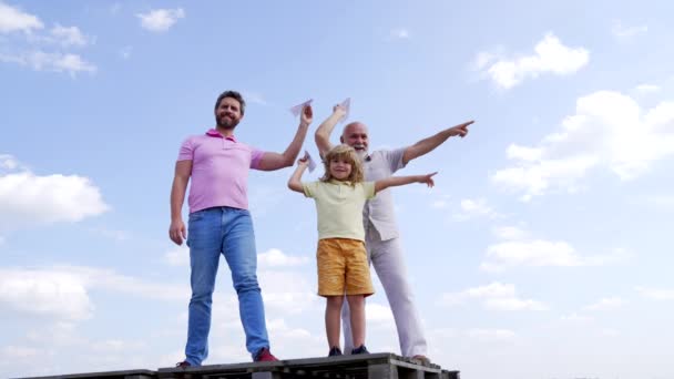 Happy family of boy kid with dad and grandad hold paper planes pointing fingers sky-high, aiming — ストック動画