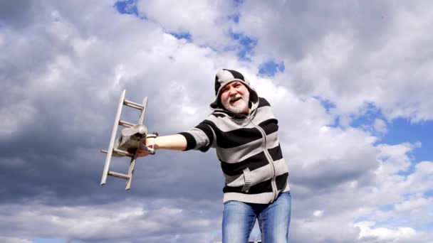 Happy greybeard man imagine flying on wooden plane in sky, pretend fly — ストック動画