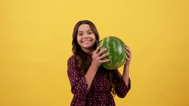 Щаслива дитина тримає водяну диню на жовтому фоні, фрукти — стокове відео