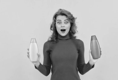 Şaşırtıcı kızıl saçlı kız kıvırcık saçlı saç şampuan şişesinin vücut bakımını seçiyor, kuaför.