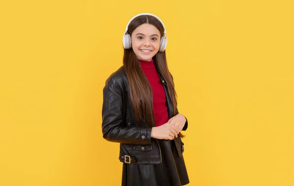 Positive teen girl listen music in headphones on yellow background, education online — 스톡 사진