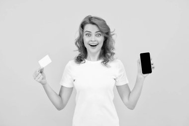 Heyecanlı genç bayan cep telefonu kartı kullanarak sarı arka planı izole etti..