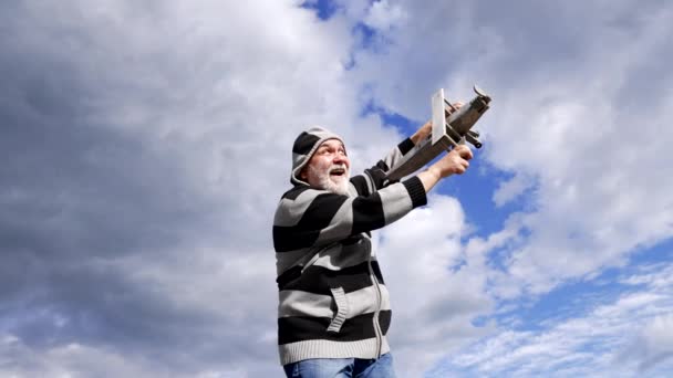Happy elderly man pretend fly on model aircraft sky-high, flying — Stock Video