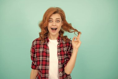 Şaşkın kızıl saçlı, kıvırcık saçlı, kareli gömlekli, moda düşkünü bir kadın.