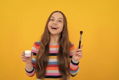 Mutlu çocuk makyaj malzemelerini fondöten, fırça sarısı arka plan, makyaj.