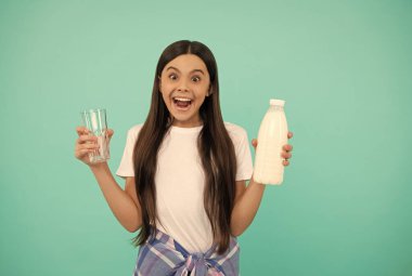 Şaşkın çocuk elinde bardak ve süt şişesi tutuyor. çocuk sütlü içecek ürünü.