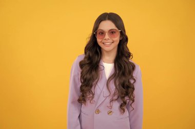 Şık mor ceketli, sarı arka planda güneş gözlüklü, şık, mutlu çocuk..