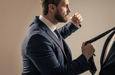 Saldırgan menajer, erkek meslektaşını yumrukladı. Kravatı gri arka plan, saldırganlık..