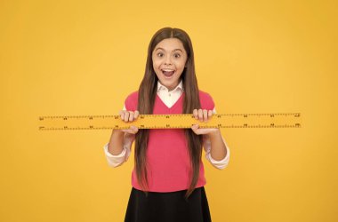 Şaşırmış çocuk matematik ve ölçü öğrenmek için cetvel kullanıyor.