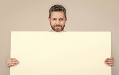 Gülümseyen olgun sakallı adam boş beyaz kağıt pankartın arkasında fotokopi alanı sunuluyor.