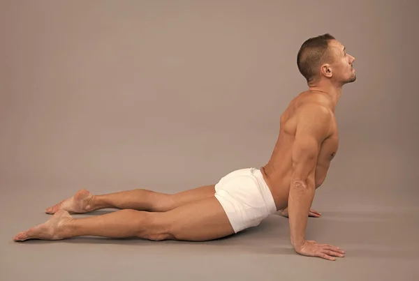 Yogi uomo fare back-bending asana cobra yoga posa sfondo grigio, posizione del corpo — Foto Stock