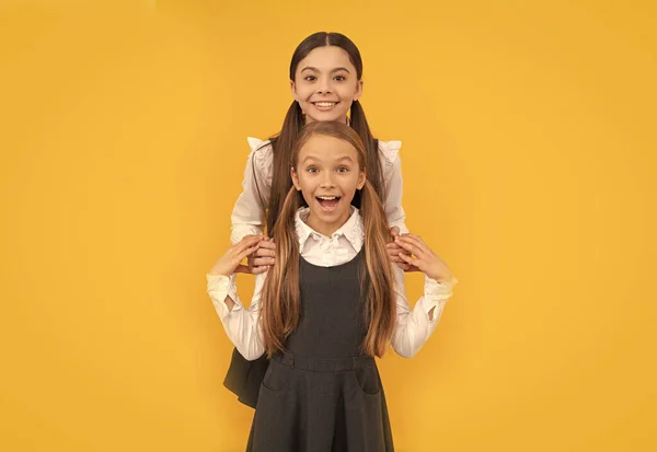 Felices amigos de la escuela abrazan en uniformes formales fondo amarillo, amistad —  Fotos de Stock