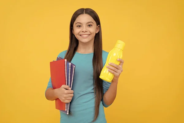 Felicidade infantil. miúdo feliz vai fazer trabalhos de casa com bloco de notas. adolescente estudante segurando água — Fotografia de Stock