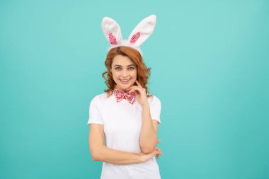 Mavi arka planda tavşan kulaklı gülümseyen Paskalya kadını.
