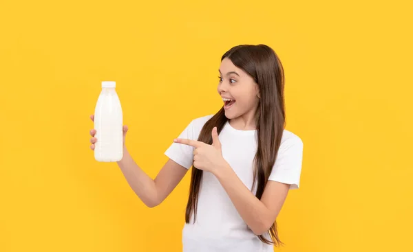 Κατάπληκτος παιδί σημείο δάχτυλο στο γαλακτοκομικό προϊόν ποτών. έφηβος κορίτσι πρόκειται να πιει γάλα. — Φωτογραφία Αρχείου