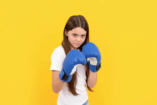Angry child fighting in boxing gloves on yellow background — 스톡 사진