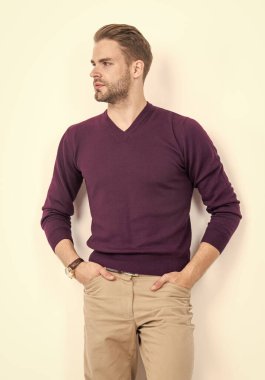 Ciddi görünüşlü çekici bir adam. Ellerini pantolonunun cebinde tutuyor. Moda tarzında.