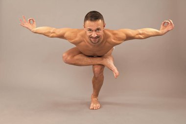 Yogi adam tek bacaklı sandalye yogası yapıyor utkatasana eğitiyor asana çömeliyor, dengede duruyor.
