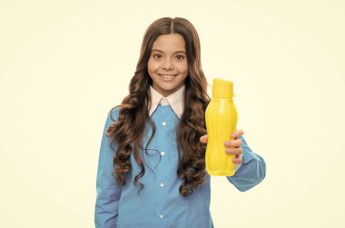 Mutlu çocuk, sarı plastik şişeyi beyaz ve içilebilir içeceklerle izole edilmiş içecek ürünüyle verir.