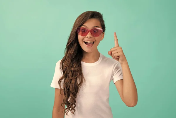 Щаслива дитина довге кучеряве волосся в сонцезахисних окулярах повсякденний стиль, натхненний ідеєю на синьому фоні, ідея — стокове фото