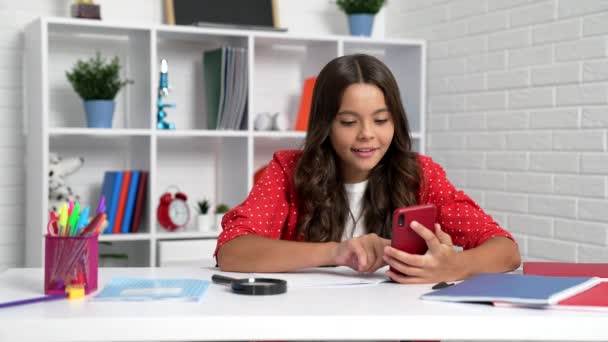 Iskolás gyerek házi feladatot csinál okostelefonnal az asztalnál, mobil oktatás — Stock videók