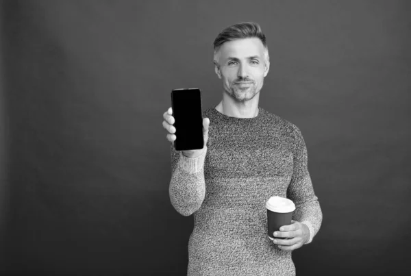 Reklám fénymásoló felülettel. mosolygós szürke fickó mutatja telefon képernyő piros háttér. — Stock Fotó