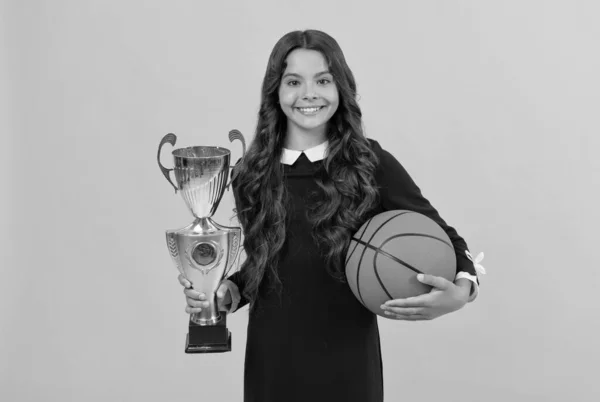 Niño alegre celebrar pelota de baloncesto y copa campeón sobre fondo amarillo, éxito deportivo —  Fotos de Stock