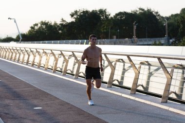 Kaslı gövdesiyle koşan atletik adam.