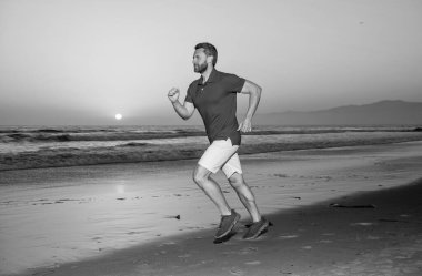 Koşucu. Spor atleti deniz batımında kazanmak için hızlı koşar. Sabah sporu aktivitesi. sağlıklı koşan adam