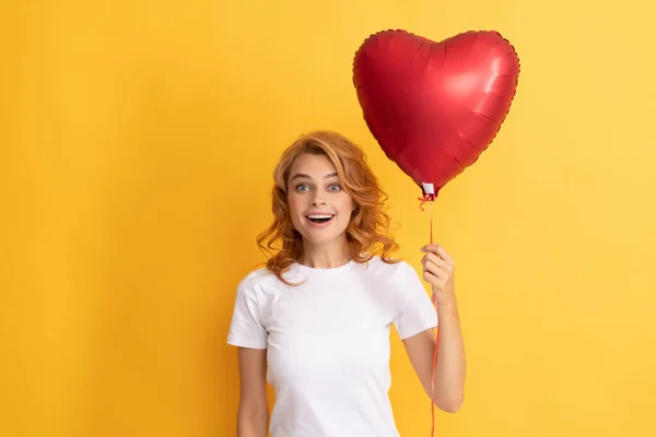 Amazed redhead woman with red heart balloon. charity and donation — стоковое фото
