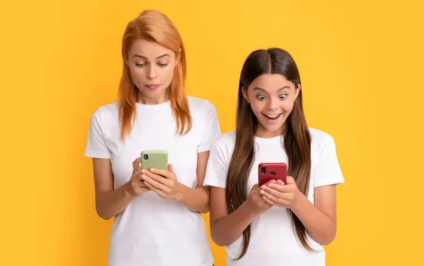 Madre e hija sorprendidas charlando en línea utilizando el teléfono inteligente moderno, mensaje —  Fotos de Stock