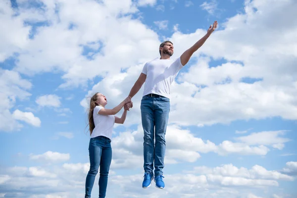 Daughter hold her daddy jumping in sky — стоковое фото