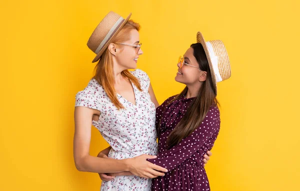 Улыбающиеся мать и дочь в соломенной шляпе на желтом фоне — стоковое фото