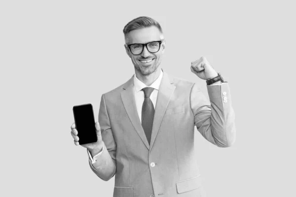 Hombre grizzled feliz mostrando la pantalla del teléfono en traje y gafas, nueva aplicación —  Fotos de Stock