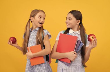 Sağlığına kavuşup okula geri dön. Mutlu çocuklar kitap ve elma tutarlar. Sağlıklı beslenme. Okul beslenmesi